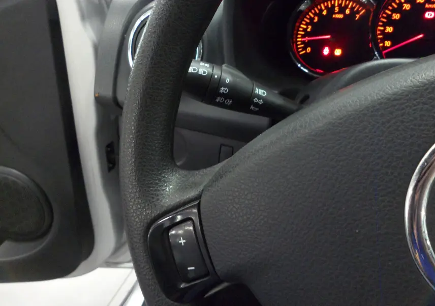 Gros plan sur le volant noir et le tableau de bord éclairé en rouge d'une Dacia Sandero Stepway Gris Platine 2016.