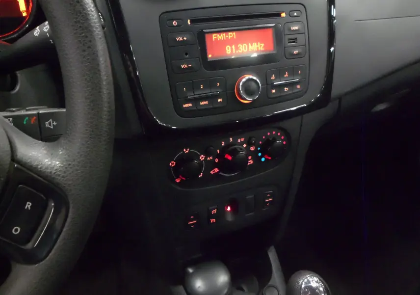 Tableau de bord et console centrale de la Dacia Sandero Stepway 2016, avec radio allumée et commandes climatisation visibles.