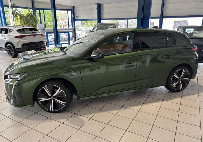 Peugeot 308 GT vert vue de profil côté gauche en intérieur avec jantes alliage noires et vitres surteintées.
