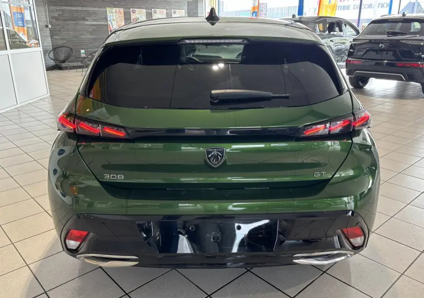 Vue arrière d'une Peugeot 308 GT 2024 vert métallisé avec feux arrière LED et diffuseur noir brillant.