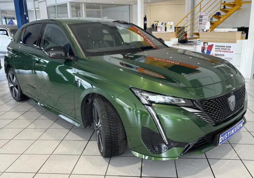 Peugeot 308 GT vert métallisé vue 3/4 avant droit, calandre noire brillante et feux LED griffés.