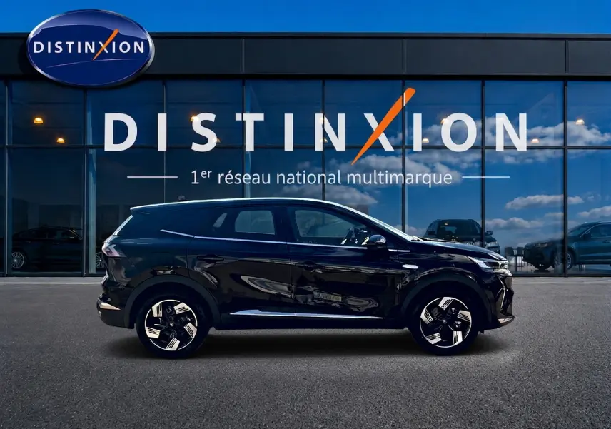 Profil droit d’un Renault Symbioz noir étoile, SUV hybride 2026, avec jantes alu distinctives, devant une vitrine Distinxion.