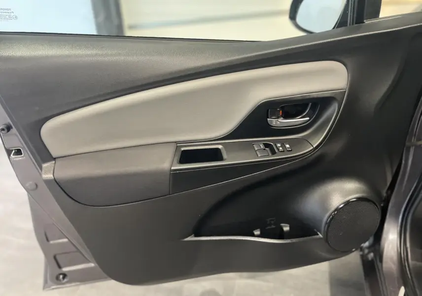 Porte avant gauche ouverte d'une Toyota Yaris hybride gris foncé, avec commandes de vitres et haut-parleur intégré.