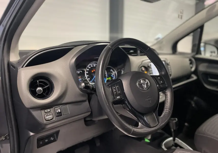Intérieur de la Toyota Yaris hybride 2020 vu côté gauche, volant cuir noir et tableau de bord gris clair.