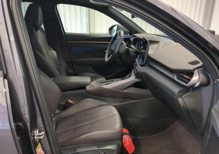 Intérieur avant du CUPRA TERRAMAR 2024 en cuir noir avec tableau de bord texturé et éclairage d'ambiance bleu visible.