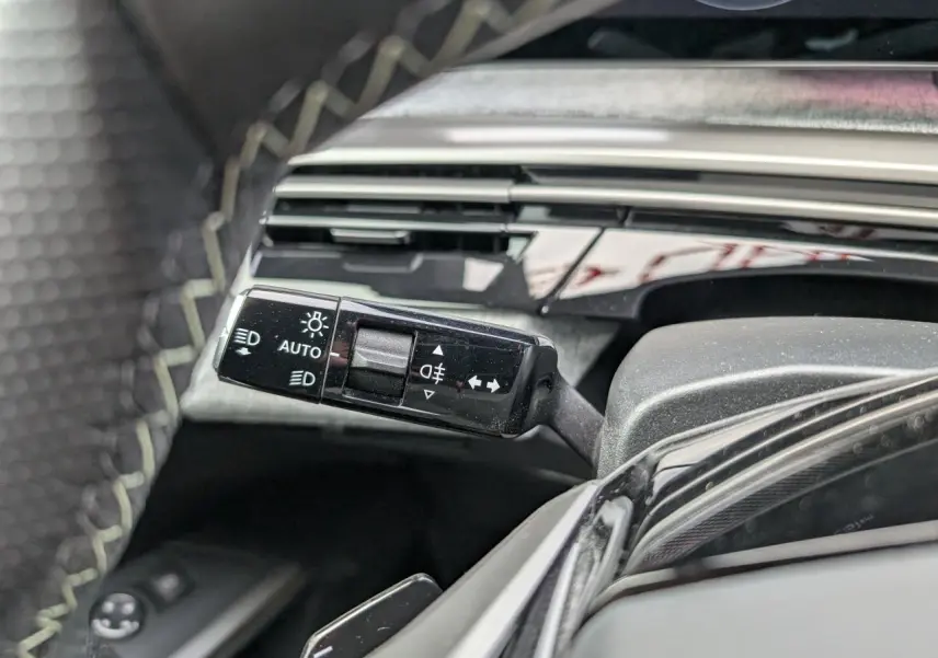 Gros plan sur la commande des feux et clignotants côté gauche du Peugeot 3008 GT 2025 bleu métallisé.