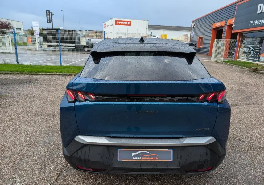 Vue arrière d’un Peugeot 3008 hybride bleu métallisé avec feux arrière à griffes LED et bandeau noir laqué.
