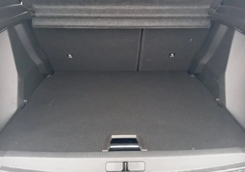 Coffre vide en vue arrière du Peugeot 2008 Hybrid blanc, montrant l'espace de chargement et la moquette noire.