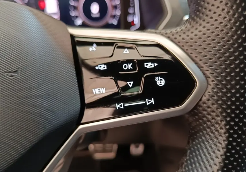 Gros plan sur les commandes multifonctions noires du volant perforé du Volkswagen Tiguan blanc 1.4 eHybrid 2023.