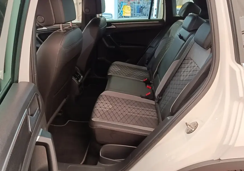 Vue intérieure côté arrière droit du Volkswagen Tiguan blanc 2023, sièges arrière en cuir et tissu gris à motifs.