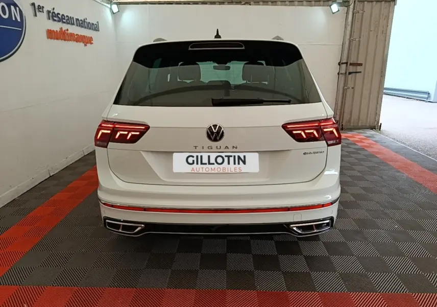 Vue arrière d'un Volkswagen Tiguan blanc hybride rechargeable 2023 avec feux LED et double sortie d'échappement intégrée.