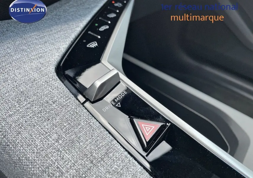 Gros plan sur la console centrale du Peugeot 3008 Hybrid 2025, bouton Drive Mode et signal d'alerte sur surface noire brillante.