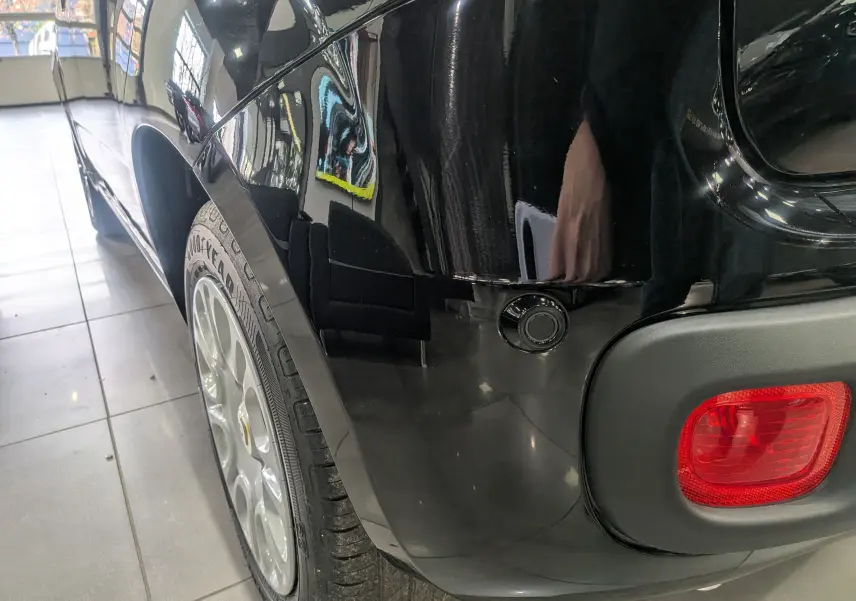 Gros plan sur l'aile arrière gauche noire cinéma d'une Fiat Panda 1.0 70 CH Hybrid City avec feu arrière et capteur de stationnement.