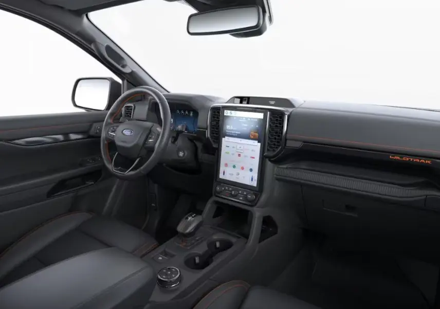 Vue intérieure côté conducteur du Ford Ranger Wildtrak 2025, tableau de bord noir avec surpiqûres orange et écran tactile vertical.