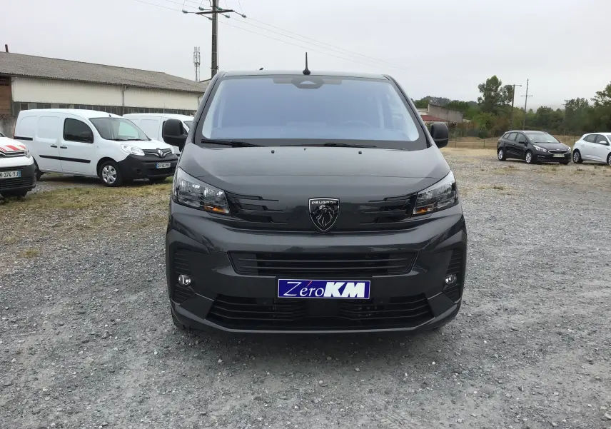 Vue frontale d’un Peugeot Expert Cabine Approfondie gris titane avec logo lion noir et plaque Zero KM visible.