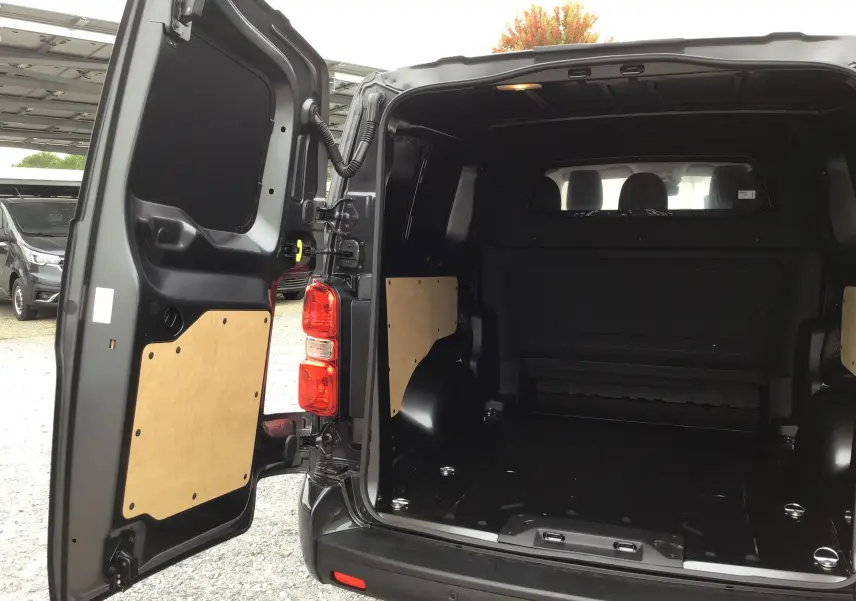 Vue arrière ouverte du Peugeot Expert XL gris titane montrant l'espace de chargement vide avec protections en bois sur les portes.