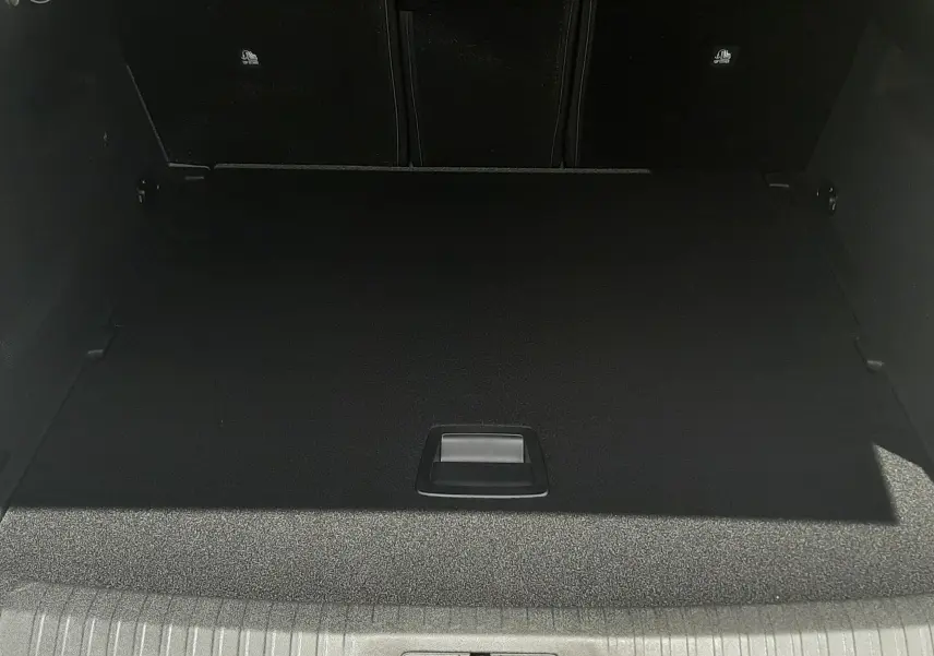 Coffre ouvert vu de face du Peugeot 3008 1.2 Hybrid 145ch GT bleu Obsession, montrant le plancher plat et le rangement sous le tapis.