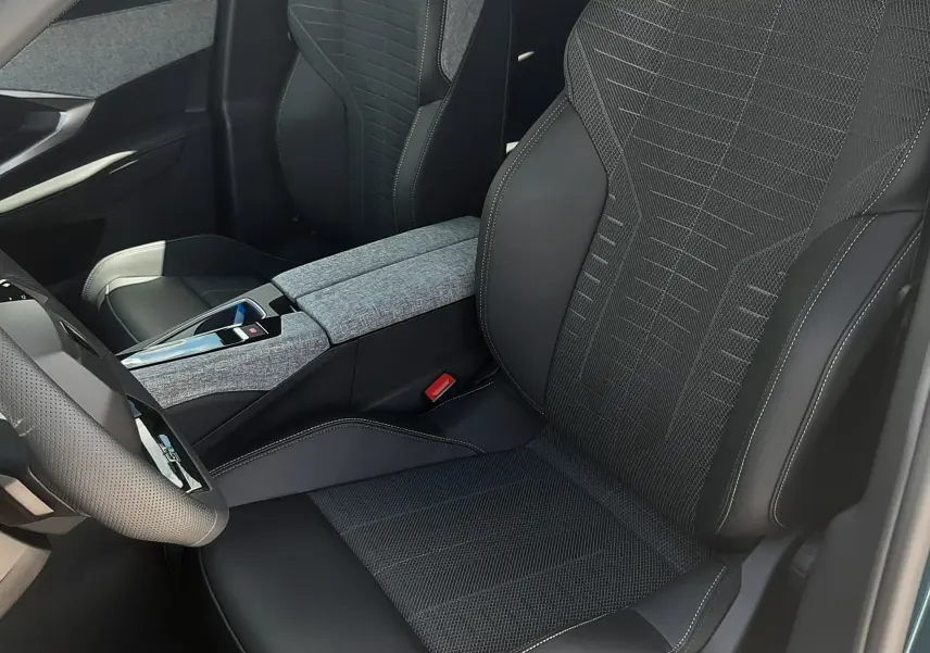 Vue intérieure côté conducteur du Peugeot 3008 1.2 Hybrid GT 2026, sièges noirs avec surpiqûres et console centrale grise.
