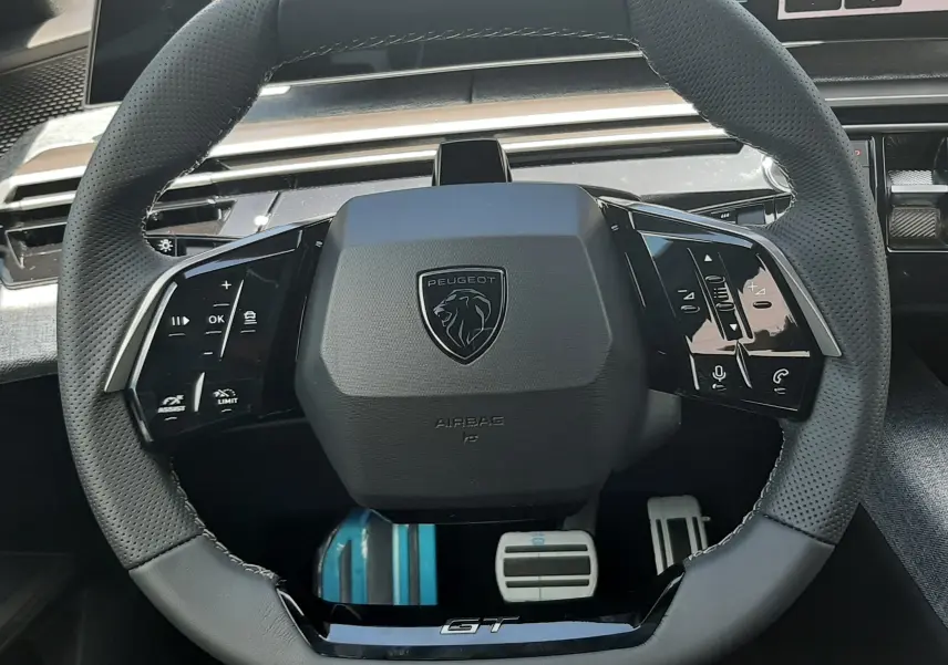 Vue rapprochée du volant cuir perforé noir du Peugeot 3008 GT 2026 avec logo lion et commandes intégrées.