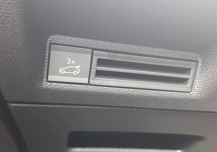 Gros plan sur le bouton d'ouverture du coffre dans l'habitacle noir du Peugeot 3008 1.2 Hybrid 145ch GT 2026.