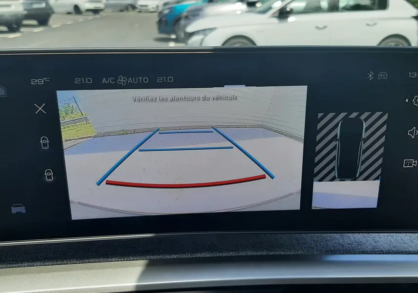 Écran intérieur du Peugeot 3008 Hybrid 2026 montrant la caméra de recul avec lignes de guidage en bleu et rouge.