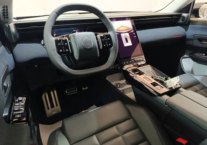 Intérieur avant du Citroën C5 Hybride 2026, vue conducteur, volant cuir et grand écran tactile vertical noir.