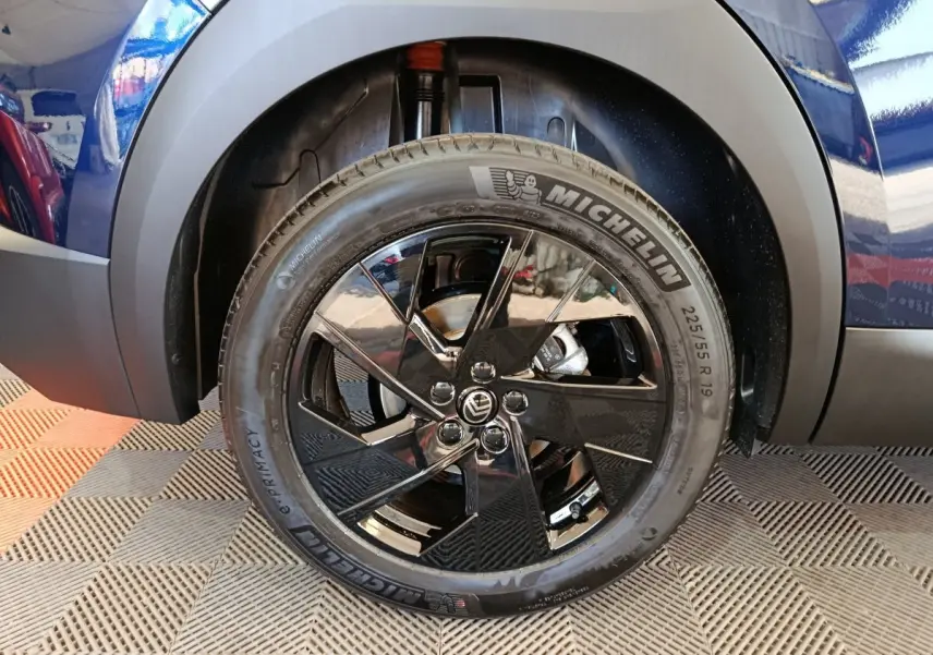 Gros plan sur la roue avant droite noire brillante d’une Citroën C5 hybride bleu 2026.