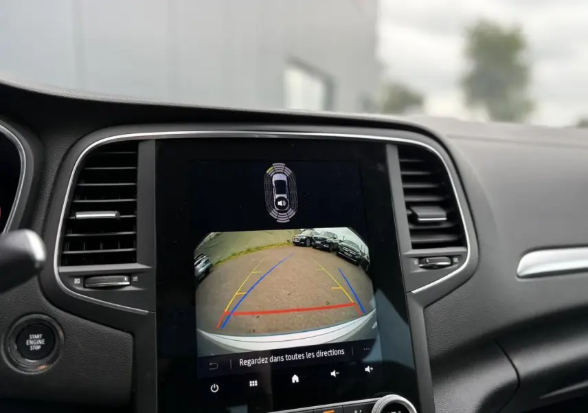 Écran tactile central affichant la caméra de recul dans un Renault Mégane Break gris Highland, vue intérieure avant.