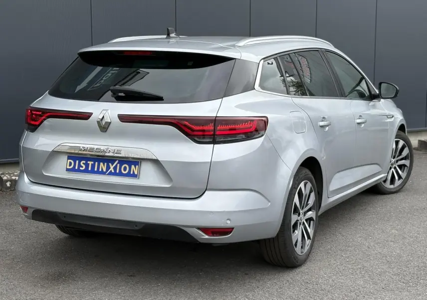 Vue 3/4 arrière droite d'une Renault Mégane Break gris Highland avec feux arrière LED et jantes alliage 17 pouces.