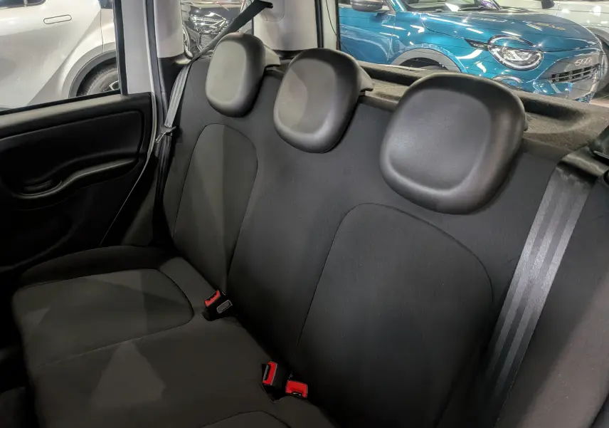 Vue intérieure de la banquette arrière noire de la Fiat Panda 1.0 Hybrid 2025, avec appuie-têtes ronds et ceintures de sécurité visibles.