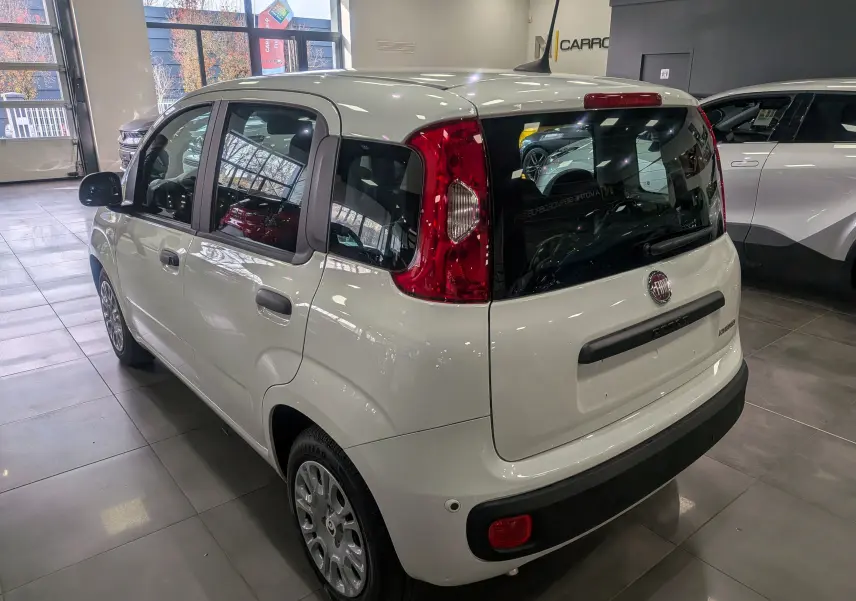 Vue 3/4 arrière droite d'une FIAT Panda 1.0 Hybrid blanche Gelato en showroom, avec feux arrière rouges et vitres teintées.