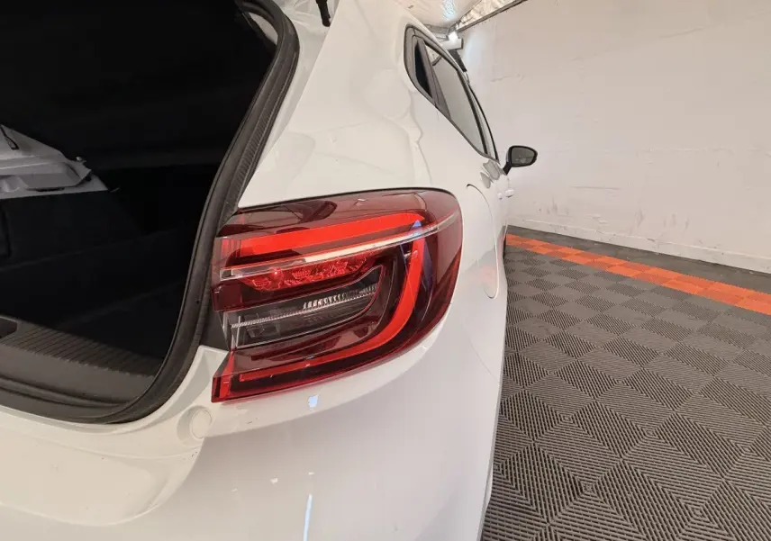 Vue arrière côté droit d'une Renault Clio blanche 2022 avec coffre ouvert et feux arrière LED visibles.