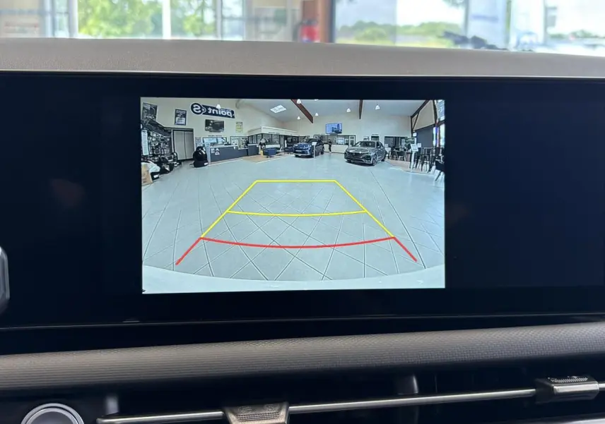 Écran de caméra de recul du Hyundai Tucson blanc Atlas montrant l’intérieur d’un showroom vu de l’arrière du véhicule.