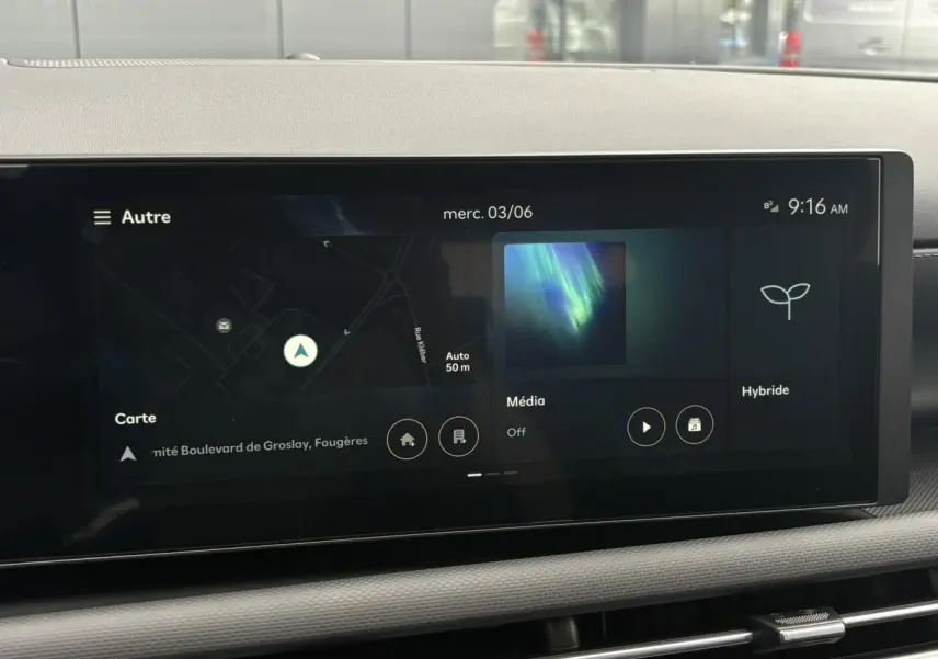 Écran tactile multimédia du Hyundai Tucson 2026 affichant navigation, média et mode hybride, vue intérieure frontale.