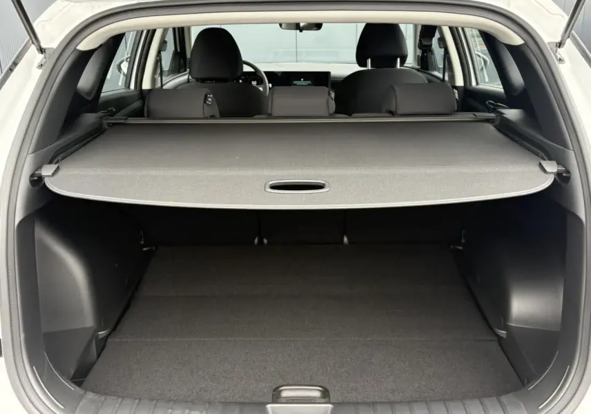 Coffre ouvert vu de l'arrière d'un Hyundai Tucson blanc Atlas 2026 avec cache-bagages déployé et intérieur noir.