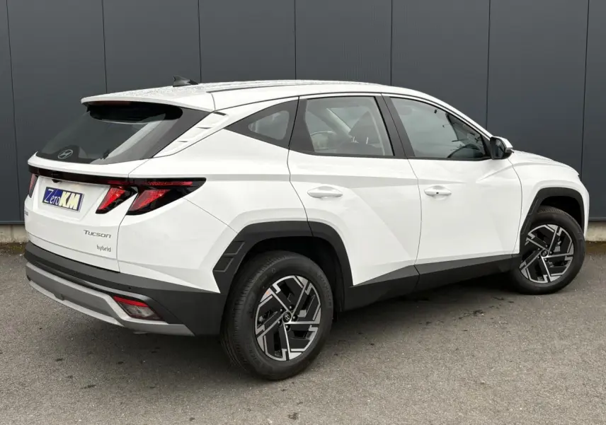 Vue 3/4 arrière droite du Hyundai Tucson blanc Atlas avec jantes alliage 17 pouces et feux arrière LED distinctifs.