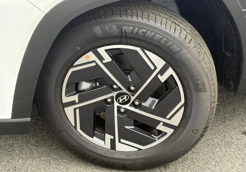 Gros plan sur la jante alliage 17'' noire et argentée du Hyundai Tucson blanc Atlas, avec pneu Michelin visible.