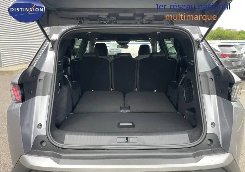 Coffre ouvert vu de l'arrière d'un Peugeot 5008 gris Artense, sièges arrière rabattus pour un grand espace de chargement.