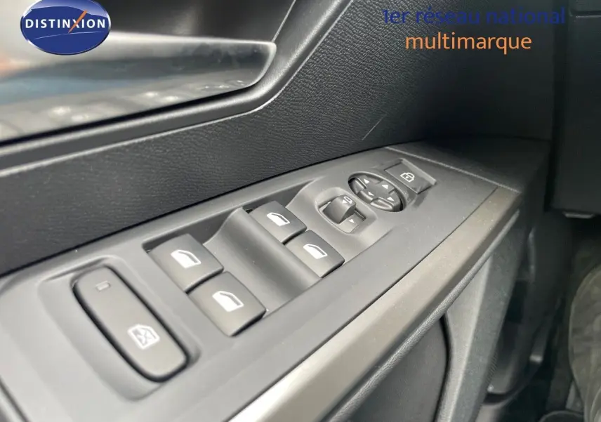 Gros plan sur les commandes des vitres côté gauche dans l'habitacle d'un Peugeot 5008 gris Artense 2025 hybride.