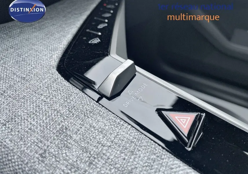 Gros plan sur la console centrale du Peugeot 5008 gris Artense, mettant en valeur le bouton Drive Mode et le triangle de signalisation.