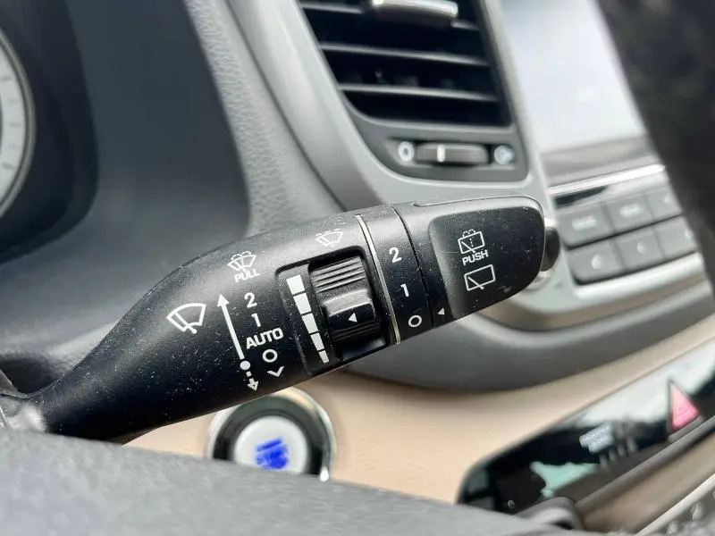 Gros plan sur la commande des essuie-glaces du Hyundai Tucson 2017, avec tableau de bord beige et bouton démarrage visible.