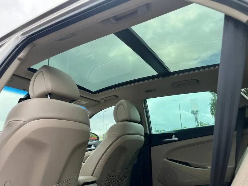Vue intérieure arrière du Hyundai Tucson 2017 White Sand avec toit ouvrant panoramique et sièges cuir beige.