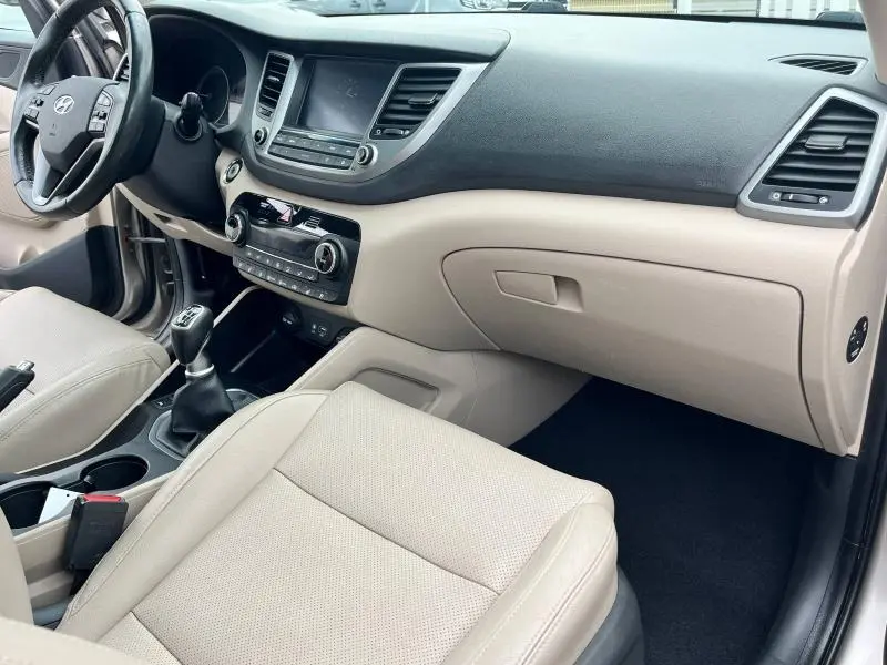 Intérieur avant droit du Hyundai Tucson 2017 avec sièges cuir beige, tableau de bord bicolore et boîte manuelle.