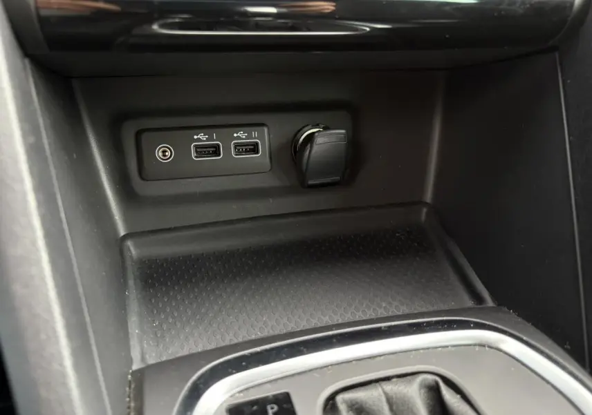 Gros plan sur la console centrale de la Renault Mégane Break 2024 avec ports USB et prise 12V, finition noire.