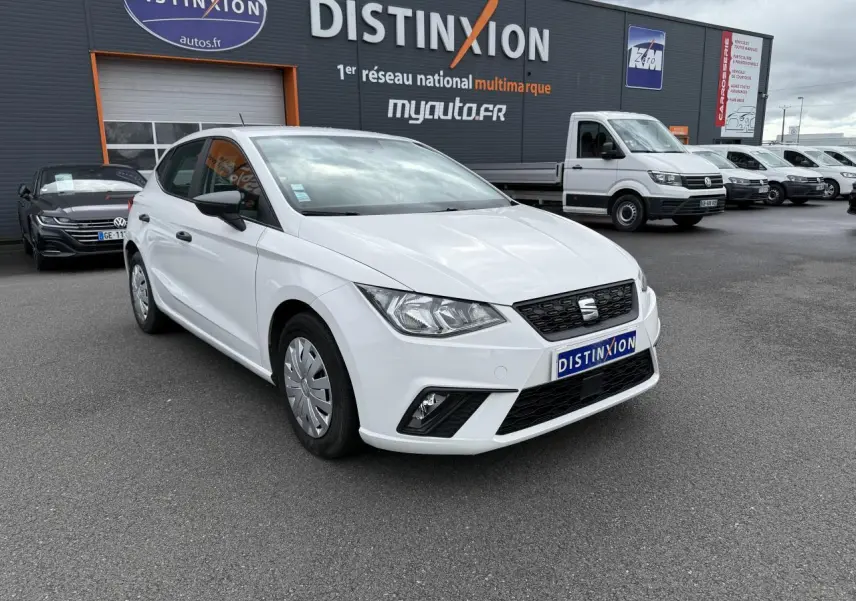 SEAT Ibiza blanc candy vue 3/4 avant droit, avec jantes enjoliveurs et rétroviseurs noirs, sur parking devant concession.