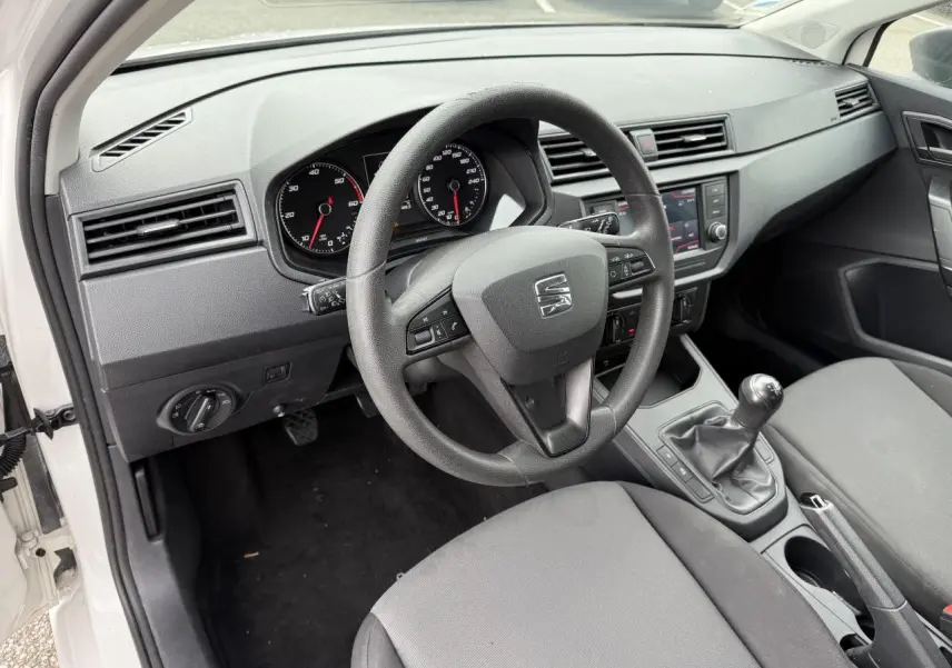 Vue intérieure côté conducteur d'une SEAT Ibiza blanche de 2019, volant multifonction et tableau de bord avec écran tactile.