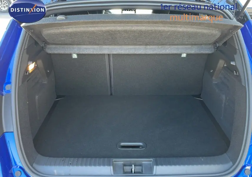 Coffre ouvert d'un Renault Captur E-Tech hybride 2025 bleu iron metal, vue arrière montrant l'espace de chargement vide.