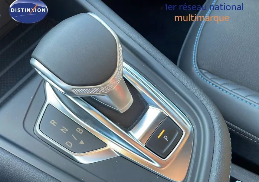 Le levier de vitesses automatique argenté et noir de la Renault Captur E-Tech hybride, avec coutures bleues visibles sur la sellerie.