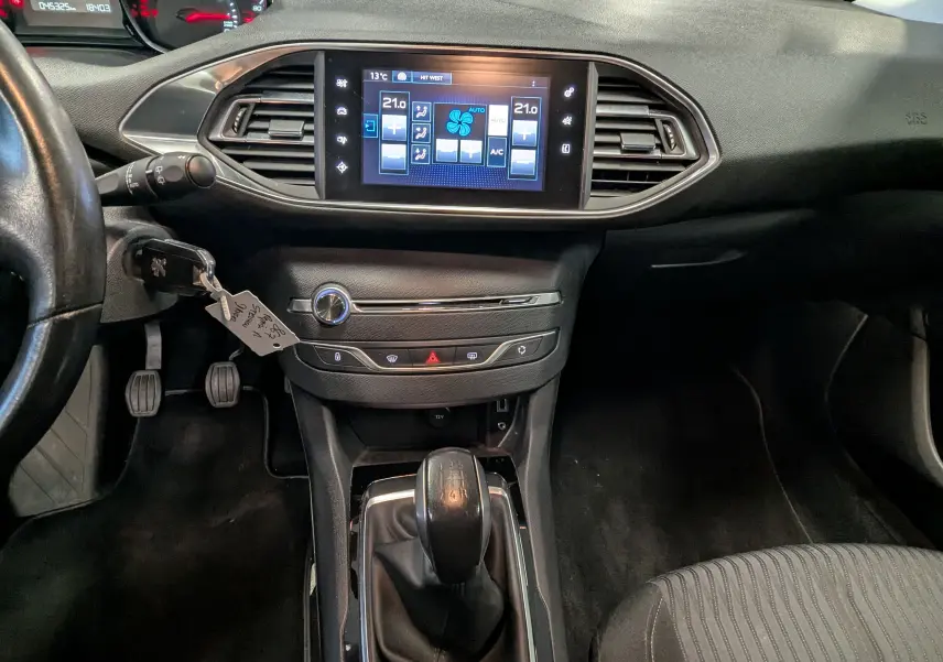 Intérieur noir de Peugeot 308 1.2 PureTech 2017, vue centrale sur tableau de bord et levier de vitesses manuel.