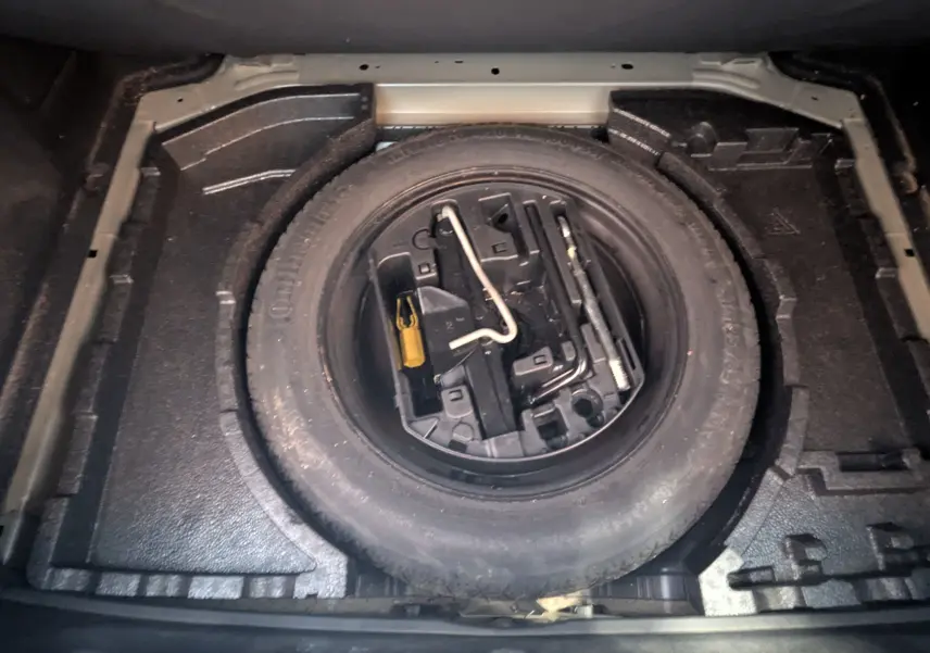 Roue de secours noire avec outils intégrés, vue plongeante sur le coffre d'une Peugeot 308 1.2 PureTech 110 Style 2017.